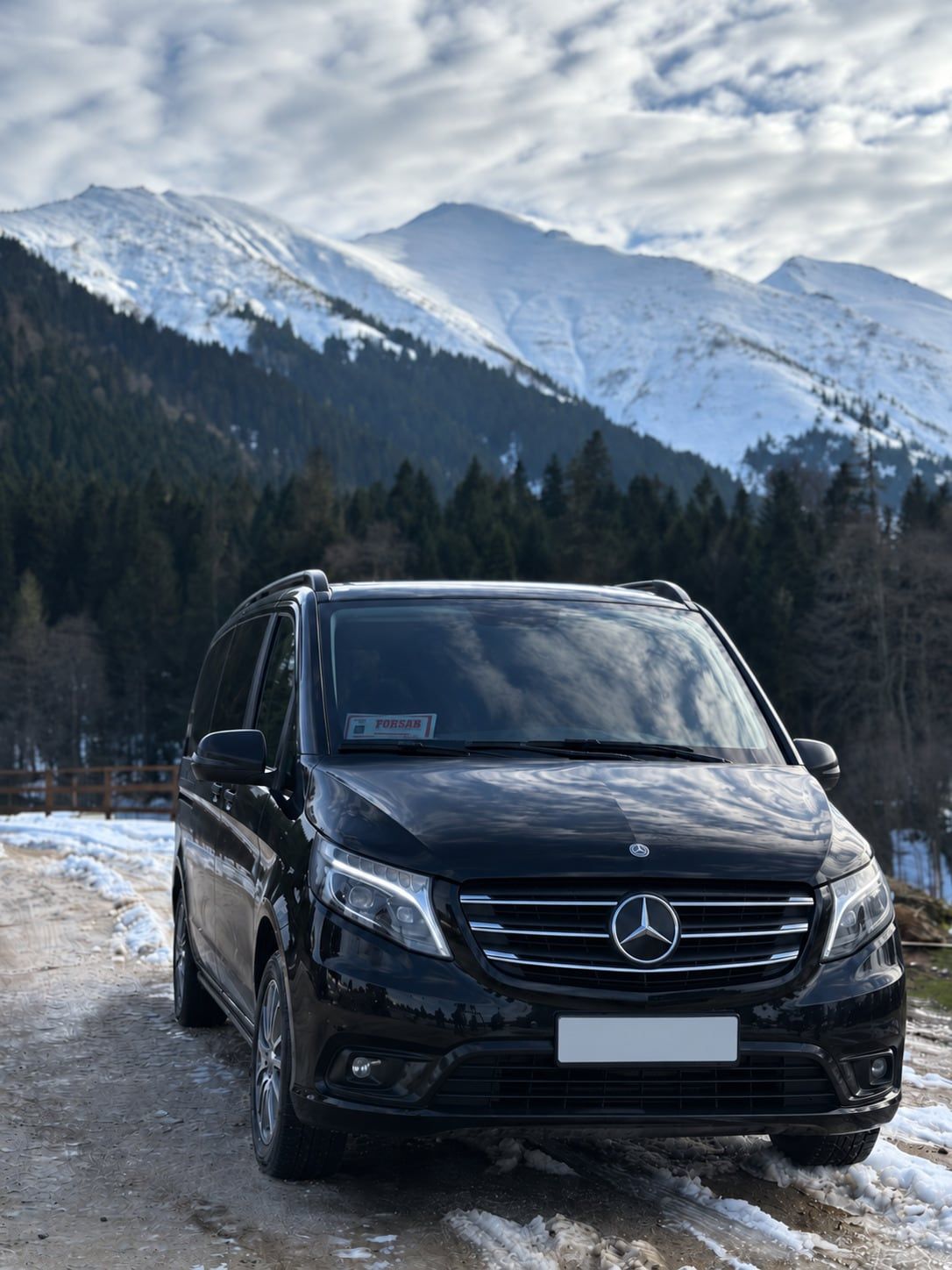 Karlı dağ zirvelerinin önünde siyah Mercedes Vito