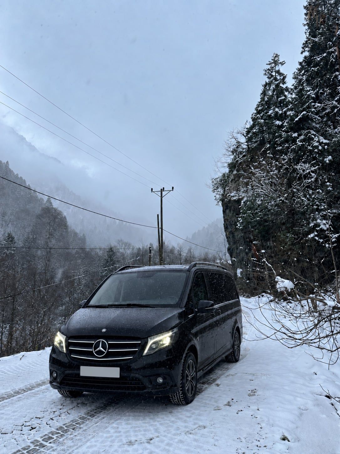 Sisli ve karlı vadi yolunda siyah Mercedes Vito