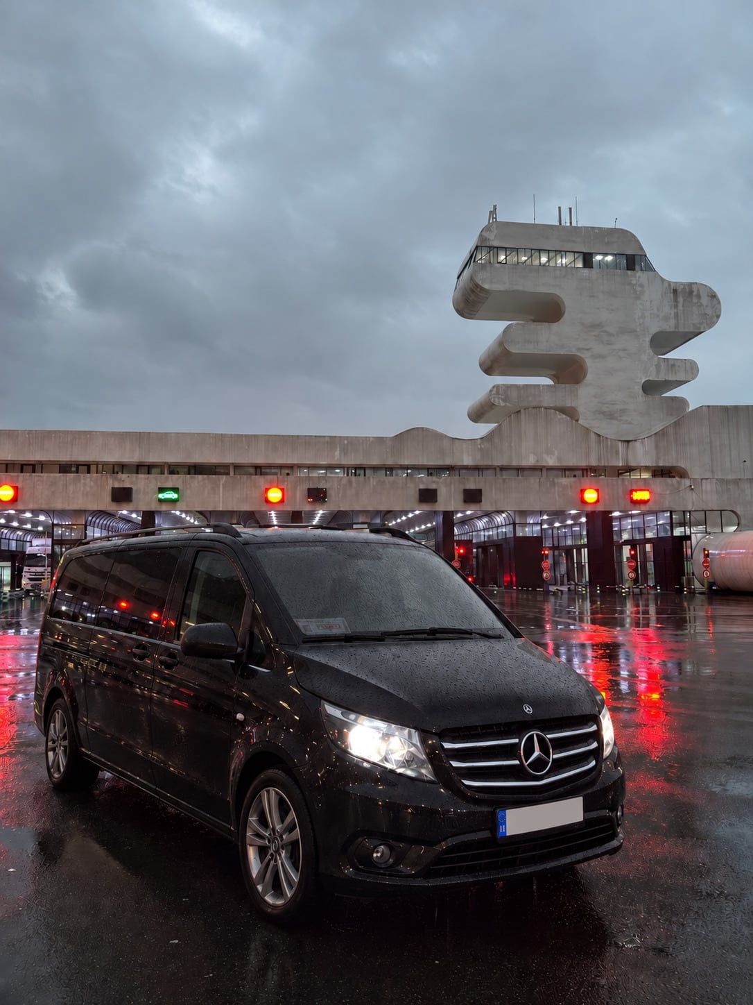 Sarp Sınır Kapısı binası önünde yağmurlu havada siyah Mercedes Vito